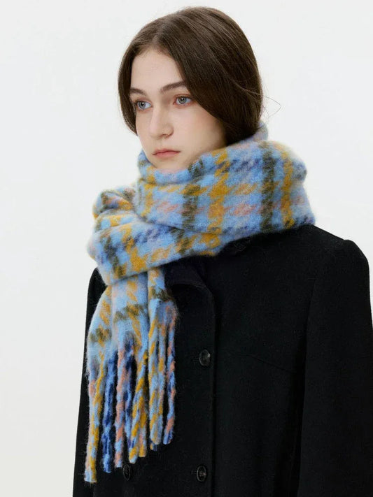 Close-up of a woman wearing a black coat and a blue and yellow plaid scarf with fringe