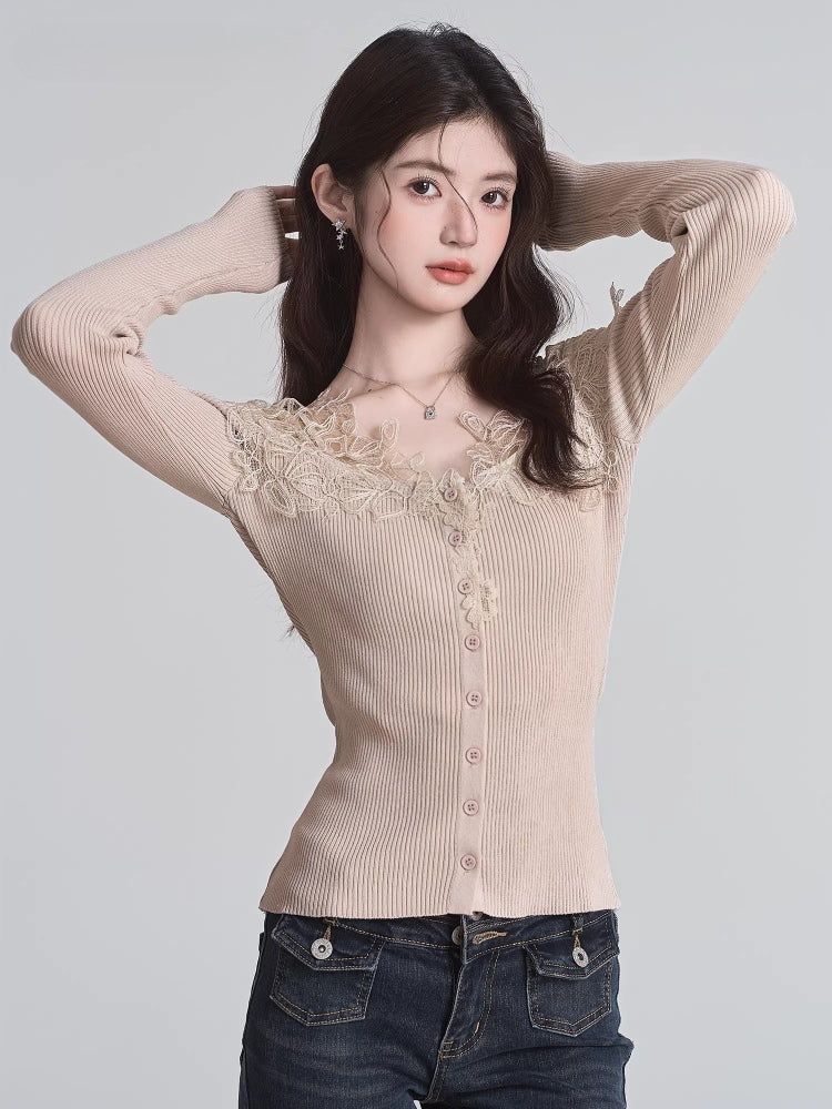 Woman posing with hands behind her head, wearing a beige ribbed knit cardigan with lace trim and a v-neck, paired with dark wash jeans.