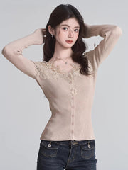 Woman posing with hands behind her head, wearing a beige ribbed knit cardigan with lace trim and a v-neck, paired with dark wash jeans.