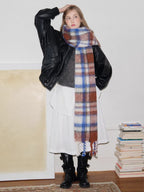 Model posing with one hand on her head, wearing a plaid scarf and stylish outfit.