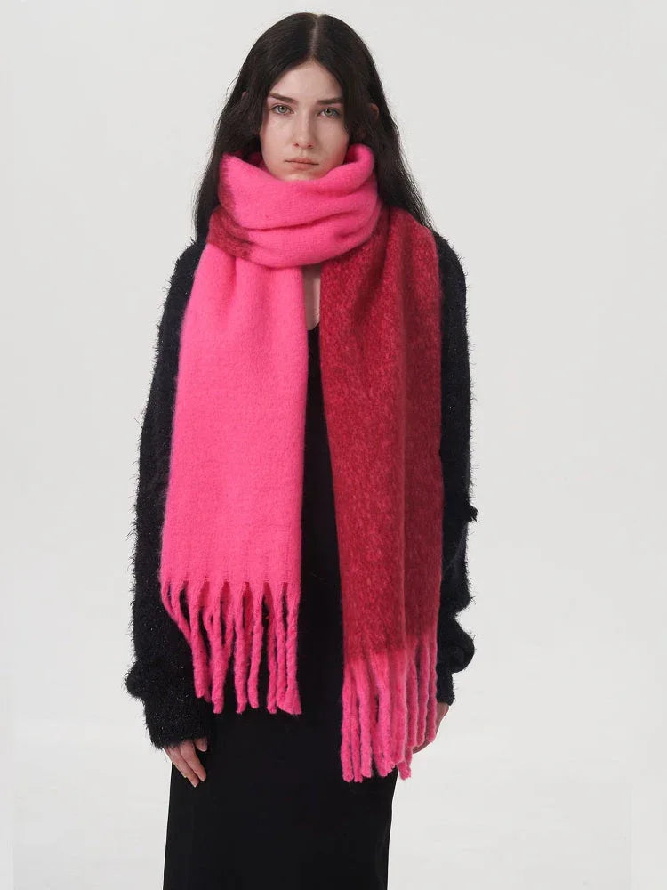 Woman wearing a black sweater and a two-toned pink and red scarf, wrapped around her neck.