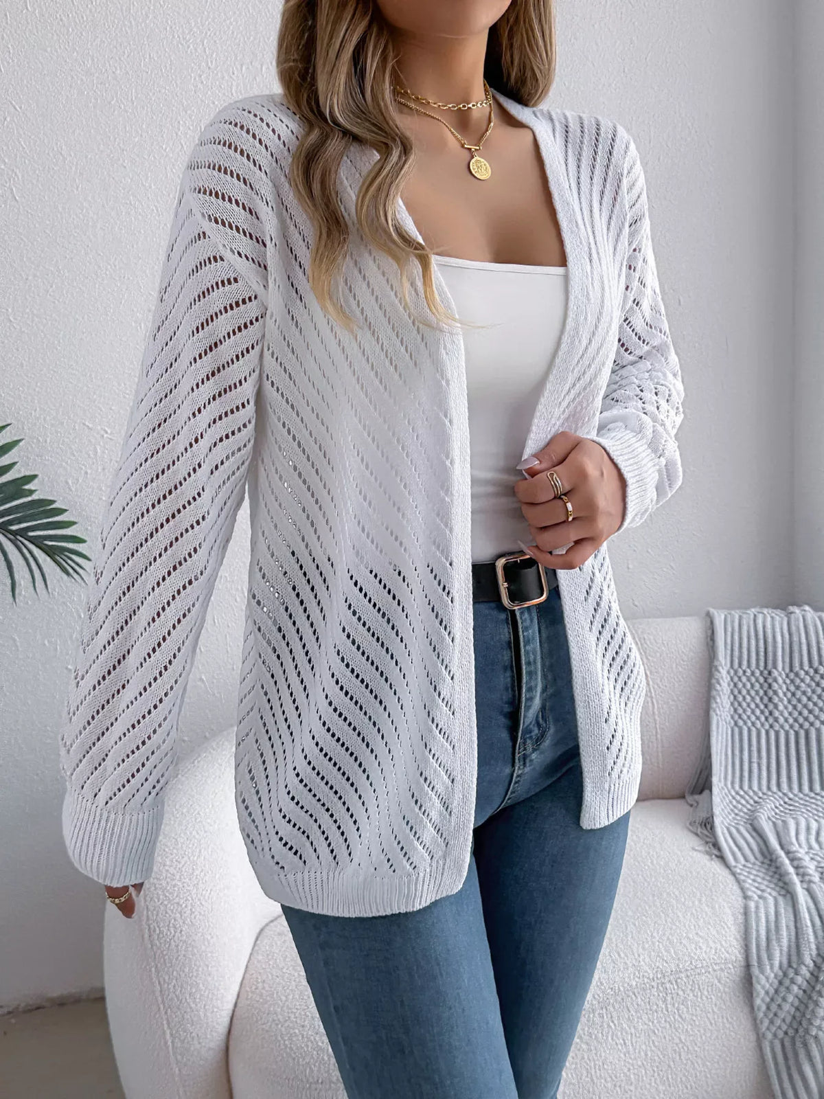 Close-up of a woman wearing a white open-knit cardigan, showing the texture and detail.