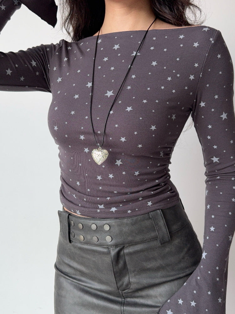 Model wearing a grey long-sleeve top with a white star print and a heart-shaped locket.