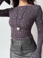 Model wearing a grey long-sleeve top with a white star print and a heart-shaped locket.