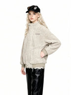 Woman in a cream-colored sherpa fleece bomber jacket, black faux leather pants, and a black baseball cap with sunglasses, with hand in pocket.