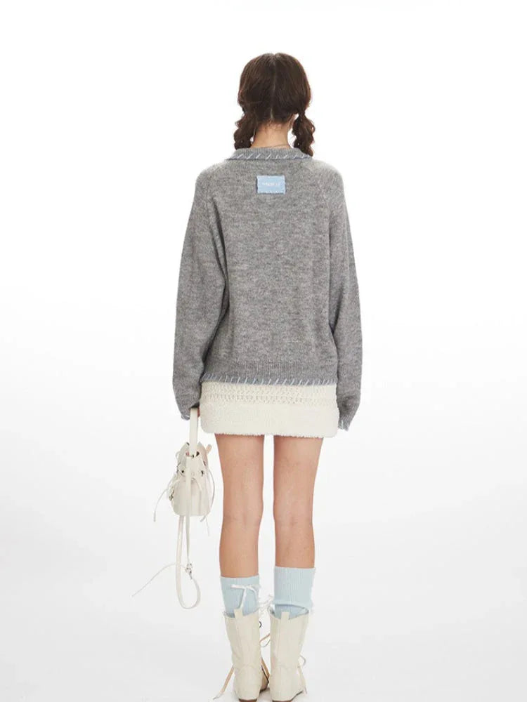 Back view of a model wearing a grey knitted cardigan with a white textured mini skirt.