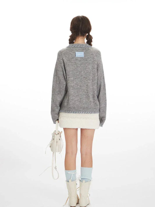 Back view of a model wearing a grey knitted cardigan with a white textured mini skirt.