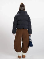 Back view of a woman in a plaid puffer jacket and wide-leg brown pants.