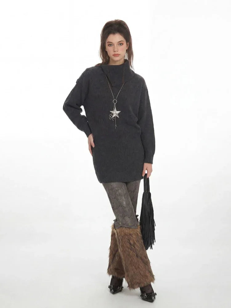 Woman wearing a charcoal grey oversized turtleneck knit tunic over patterned leggings and brown furry leg warmers, holding a black fringed handbag and wearing a star pendant necklace.