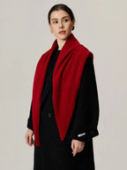 Woman wearing a red scarf draped over a black coat, front view