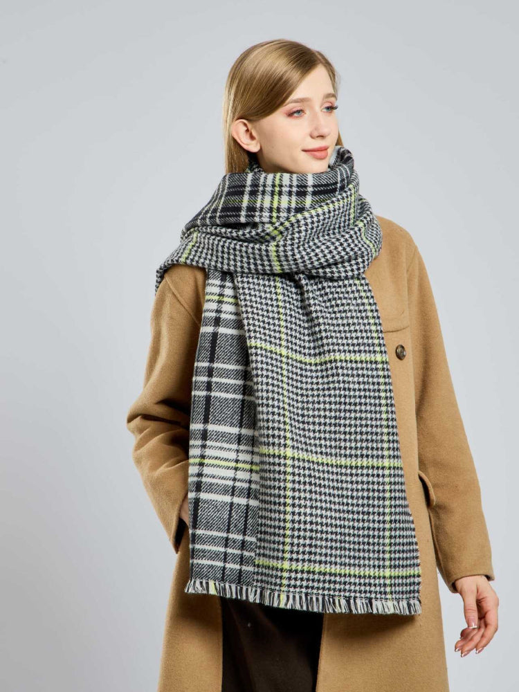 Woman in a tan coat with her large houndstooth and plaid scarf wrapped around her neck