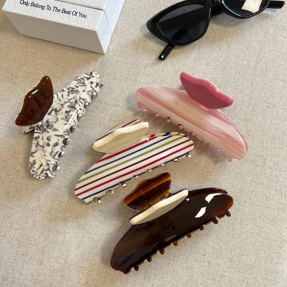 A collection of patterned hair claw clips arranged on a textured surface