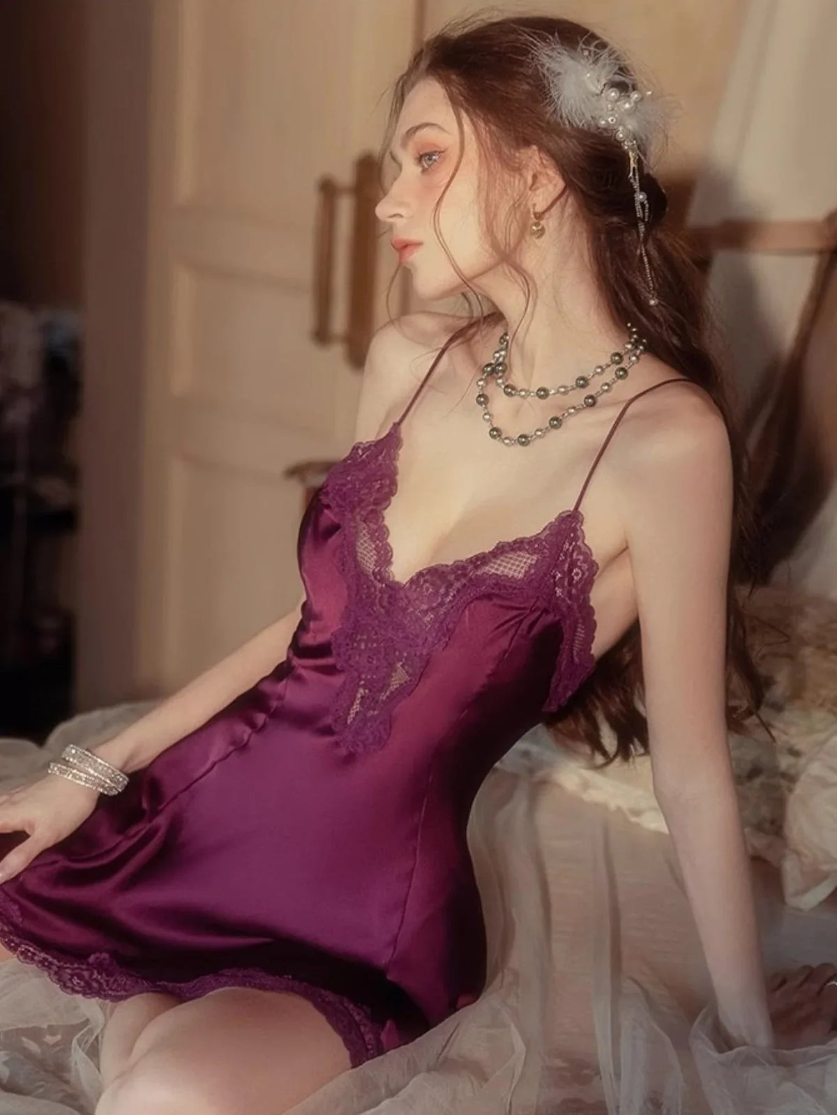 Close-up of a woman in a purple satin slip dress with lace detailing on the bust.