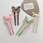 close-up of four butterfly hair sticks in pink, tortoiseshell, green and orange, and pearlescent white
