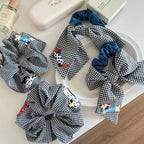 Close-up of black and white gingham scrunchies with denim bows, showcasing embroidered dog designs