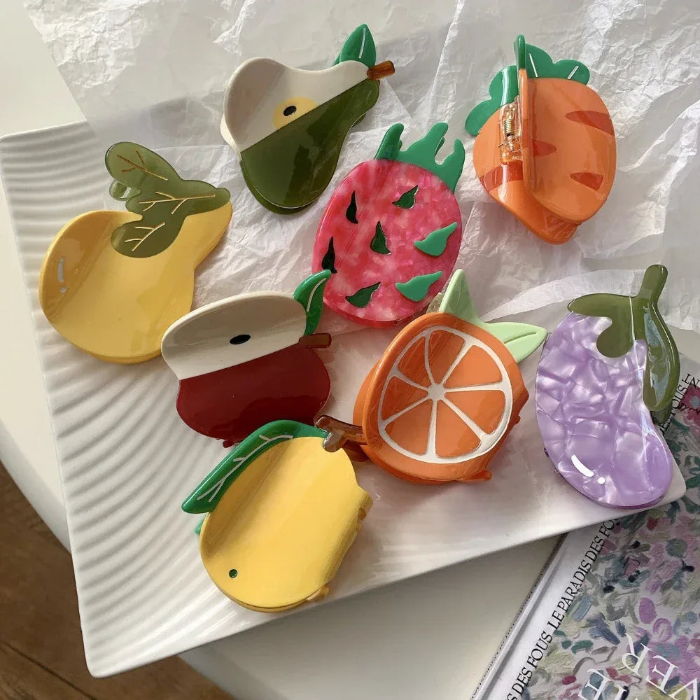 Assortment of colorful fruit-shaped hair claw clips arranged on a white plate
