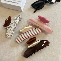 A collection of patterned hair claw clips arranged on a textured surface