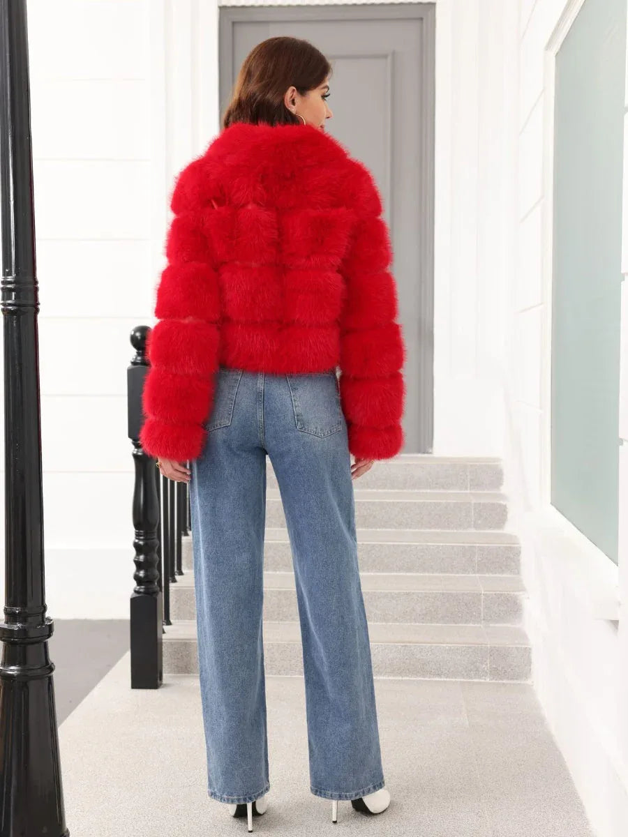Back view of a woman wearing a red faux fur cropped jacket with a grey turtleneck and blue jeans, standing on stairs.