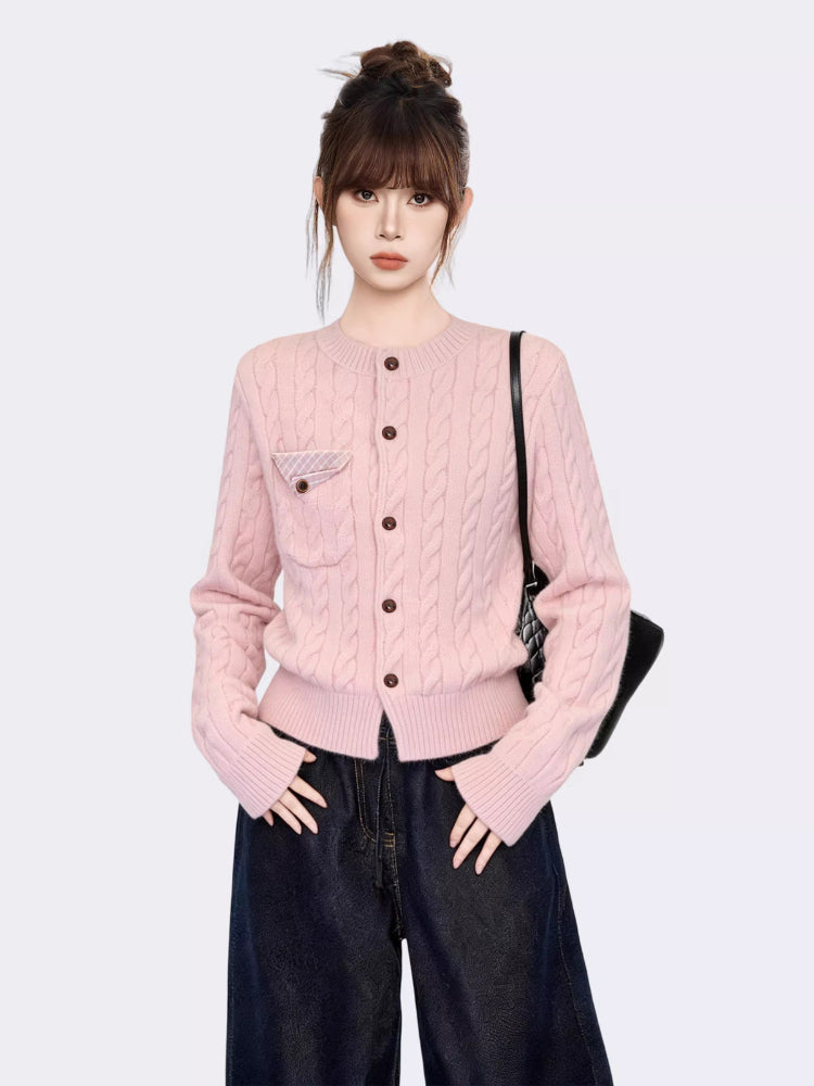 Close-up of the pink cable knit cardigan, showing the texture, buttons, and pocket detail.