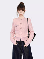 Close-up of the pink cable knit cardigan, showing the texture, buttons, and pocket detail.