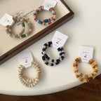 Several fuzzy hair ties with different striped patterns and bead colors, arranged on a white table.
