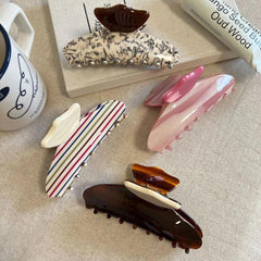 A collection of patterned hair claw clips arranged on a textured surface