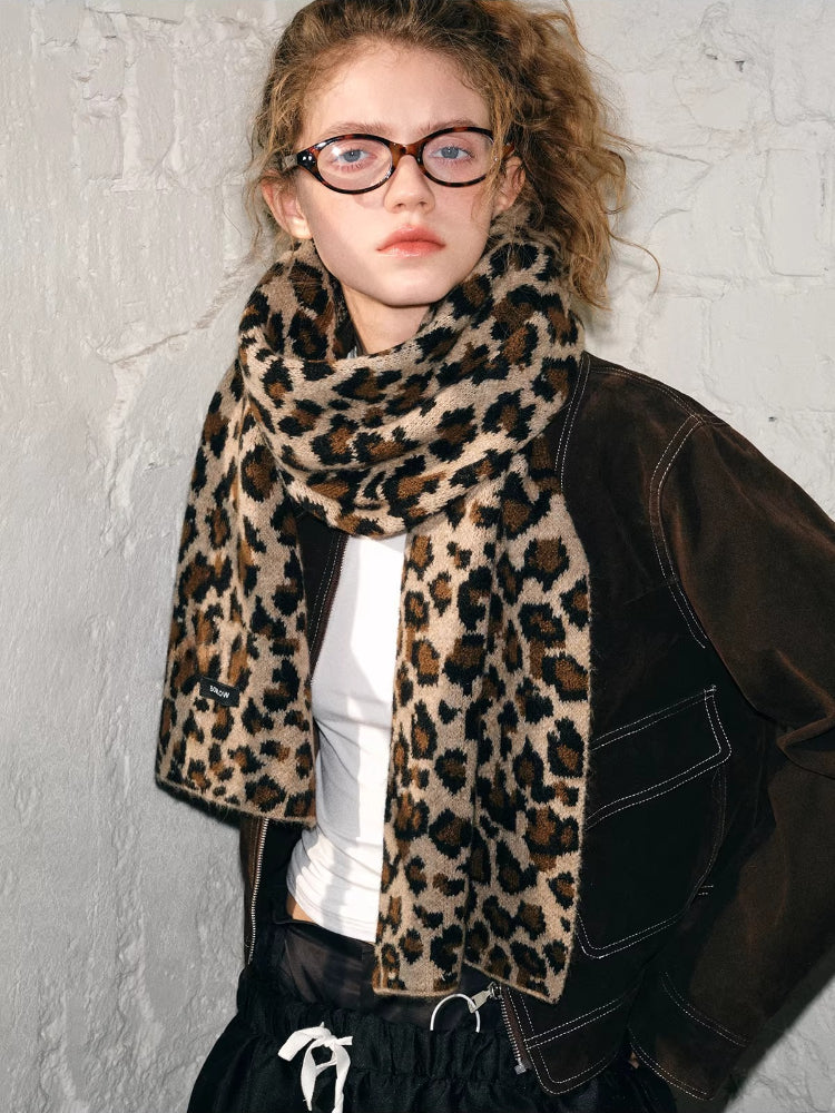 Model posing in a brown jacket and leopard print scarf, looking to the side.