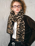 Model posing in a brown jacket and leopard print scarf, looking to the side.