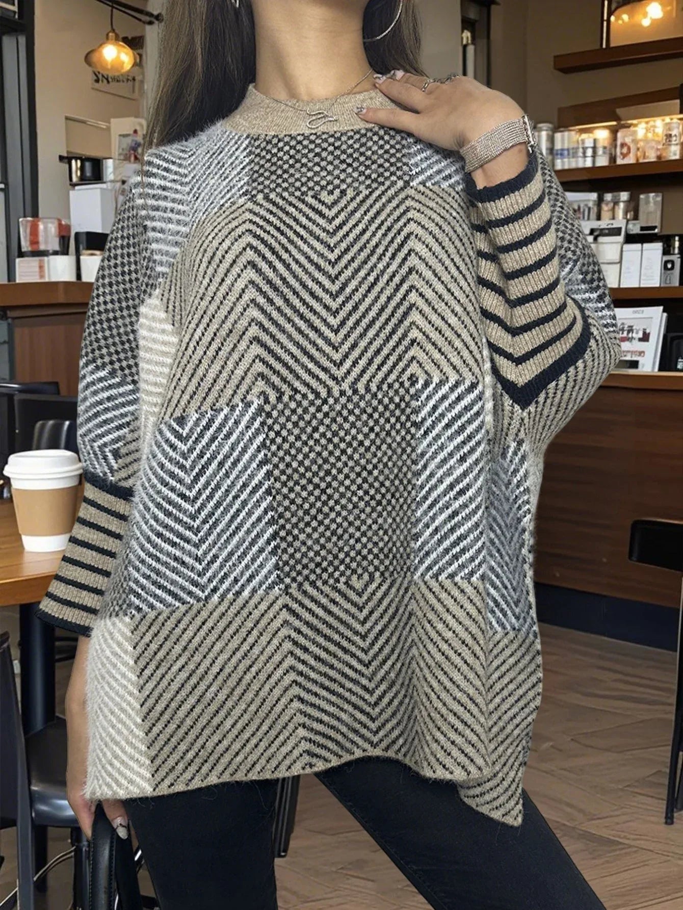 Woman wearing a geometric pattern knit poncho, with a hand on her chest