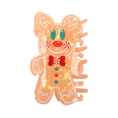 Close-up of an orange gingerbread man hair claw clip with white frosting details and red and blue candy buttons.
