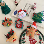 Collection of plush Christmas-themed hair accessories and ornaments including Santa, gingerbread man, Christmas tree, reindeer, gift box, and snowflake wreath