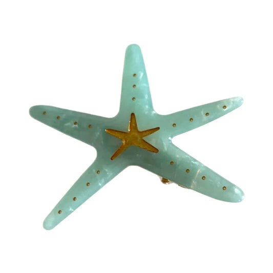 A light blue translucent acrylic starfish hair clip with a gold central star and gold dots.