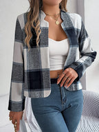 Front view of a woman wearing a cropped buffalo plaid jacket, white tank top, and blue jeans, with jewelry and a handbag.