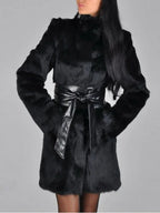 Front view of a woman in a black faux fur coat with a tied black leather belt