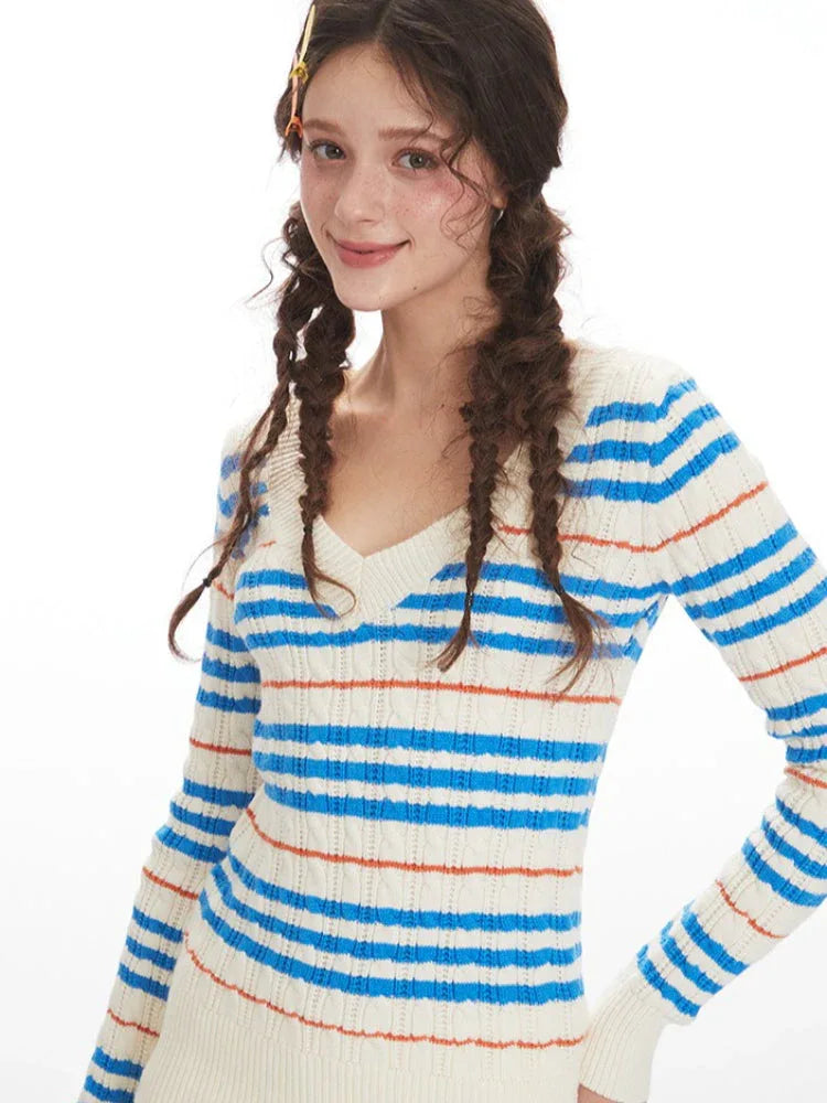 Close-up of a woman's face and upper body, wearing a striped v-neck sweater.