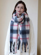 Woman wearing a cream-colored sweater and a plaid scarf with white, pink, and gray colors.