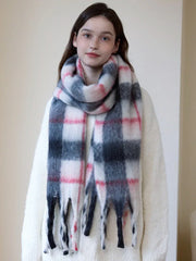Woman wearing a cream-colored sweater and a plaid scarf with white, pink, and gray colors.