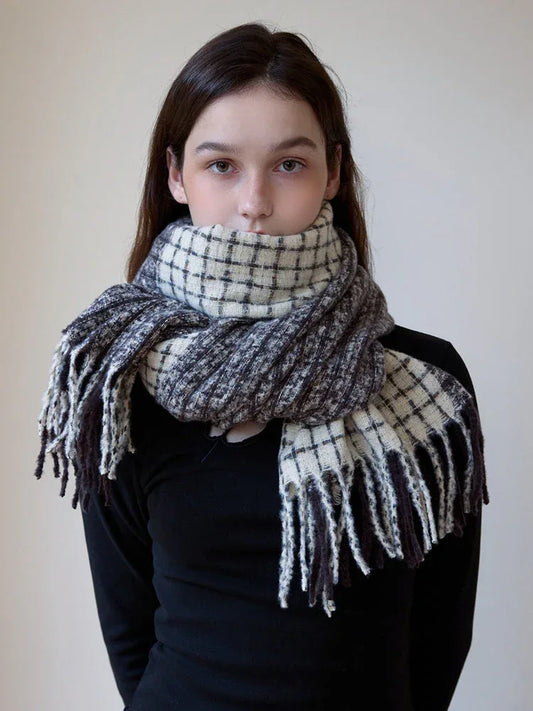 Close-up of a woman wearing a plaid scarf with fringe detail wrapped snugly around her neck.