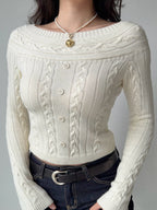 Close-up of a cream cable knit cropped sweater with an off-the-shoulder neckline and button details.