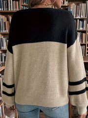 Back view of a woman wearing a black and tan color-blocked sweater with striped sleeves, in front of a bookshelf.
