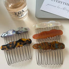 A close-up view of several cloud-shaped hair combs in different colors, displayed on a white surface with a perfume bottle and a laptop.