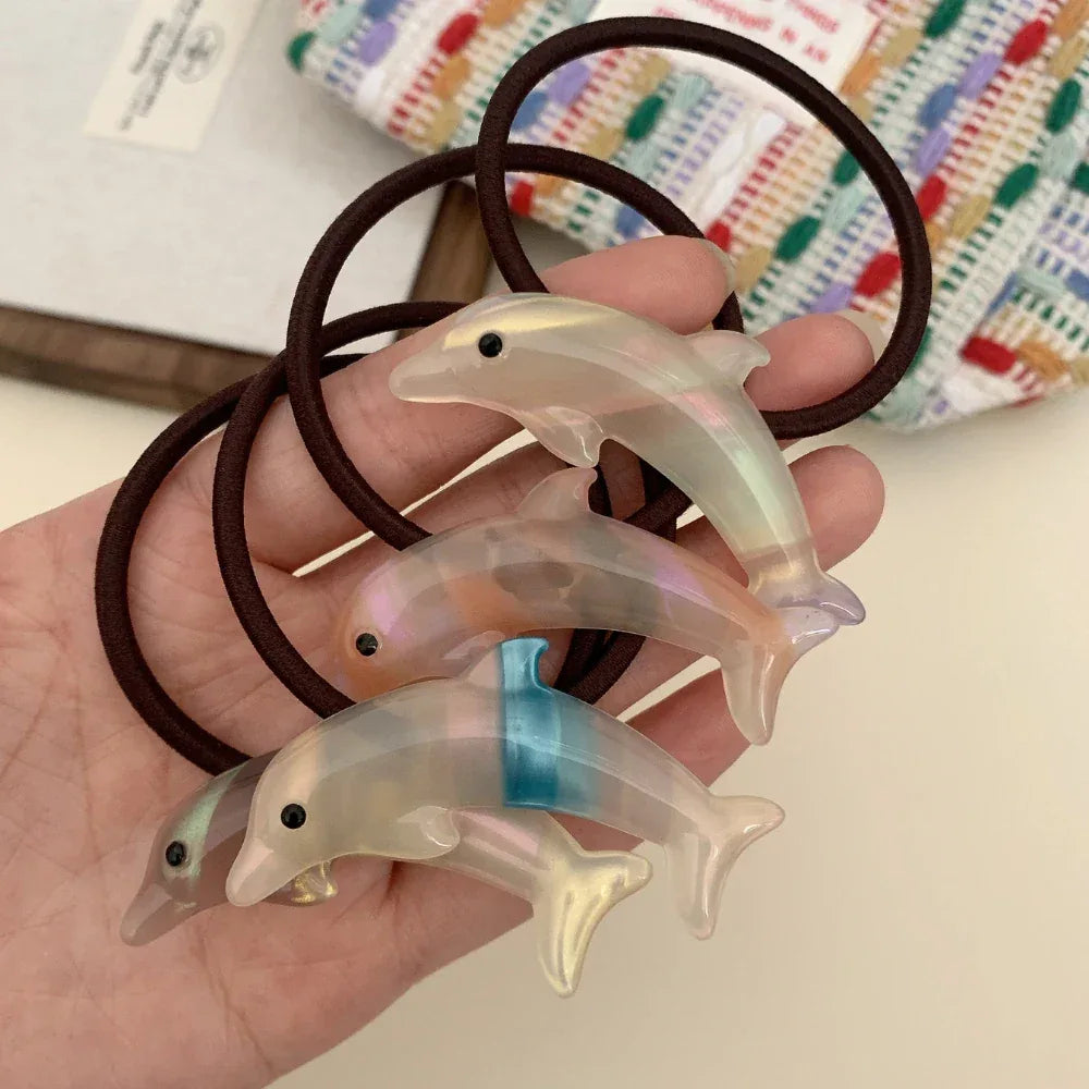 Hand holding multiple iridescent dolphin hair ties