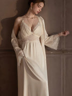 Woman holding the hem of a cream satin nightgown with lace trim.