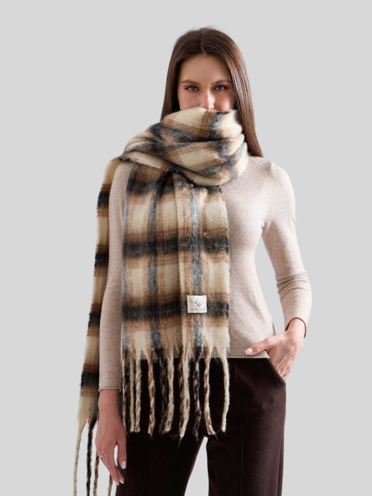 Woman wearing an oversized plaid scarf draped around her neck and shoulders, covering her lower face.