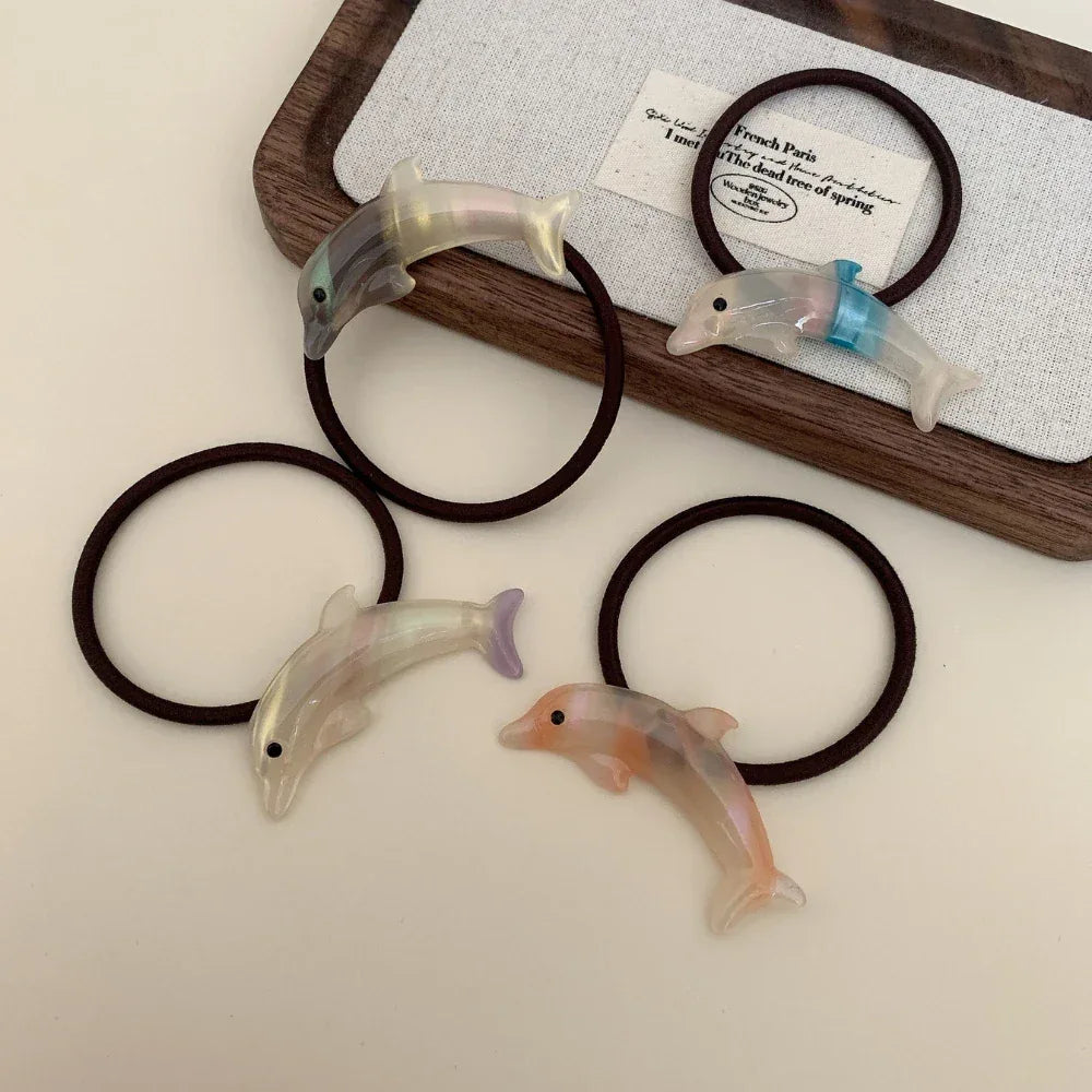Assortment of iridescent dolphin hair ties arranged on a wooden tray