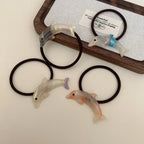 Assortment of iridescent dolphin hair ties arranged on a wooden tray