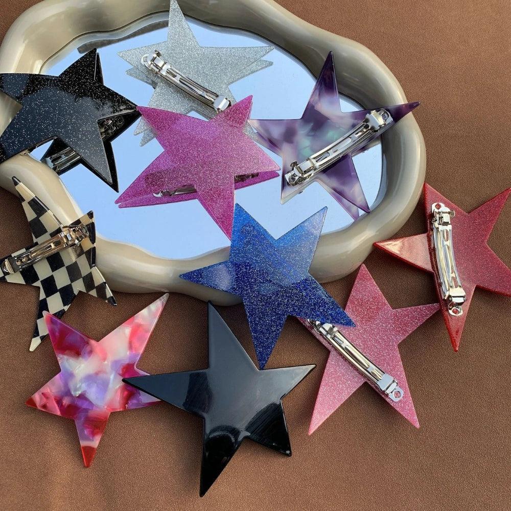 collection of star-shaped hair clips in various colors and patterns displayed on a mirror and brown surface