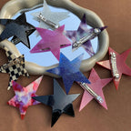 collection of star-shaped hair clips in various colors and patterns displayed on a mirror and brown surface