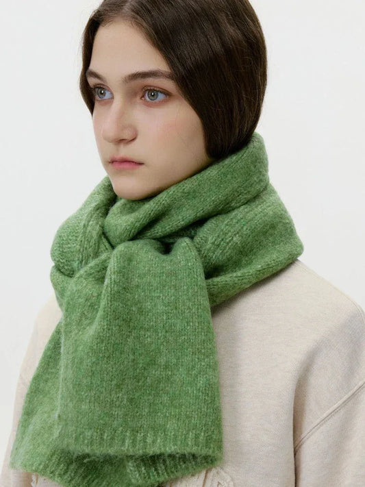 Model wearing a cream sweatshirt and a thick green knit scarf wrapped around her neck, side view.