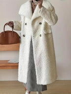 Woman wearing a long white fuzzy fleece coat with a notched lapel and double-breasted closure, holding a brown handbag.